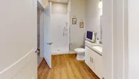 A connected layout that keeps your essentials close and your routine stress-free. Modern bathroom with elegant glass shower, granite countertop, and stylish wooden flooring.