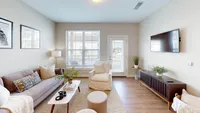 Let the light in with a large window and easy access to your private outdoor space. Bright and inviting living room with modern decor, featuring a cozy sofa, stylish armchair, and large window flooding the space with natural light.