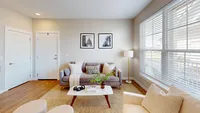 Comfortable and welcoming from the moment you walk in. Bright and cozy living room featuring a stylish beige couch, contemporary decor, and large windows with blinds, creating a warm and inviting atmosphere.