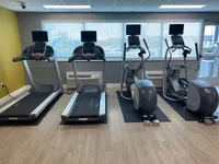 Modern fitness center with state-of-the-art treadmills and elliptical machines, featuring bright natural light and sleek design.