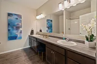 Elegant bathroom featuring a large mirror, chic lighting, and a modern vanity with decorative accents.