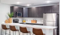 Modern style meets utility with sleek cabinetry and stainless steel appliances, including a microwave, glasstop stove, refrigerator, and dishwasher.