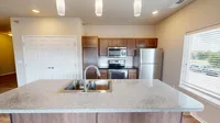 Modern kitchen with stainless steel appliances, elegant granite countertops, and ample natural light through large windows.