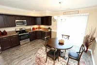 Inviting kitchen and dining area with rich dark cabinetry, modern appliances, and elegant chandelier lighting over a cozy round table.