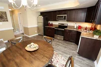 Inviting kitchen and dining area with elegant dark wood cabinets, stainless steel appliances, and a cozy wooden dining table, perfect for modern living.