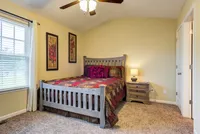 Cozy bedroom with a wooden bed frame, colorful quilt, and elegant decor in a well-lit space.