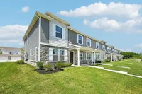 Charming row of modern townhouses with well-maintained lawns, showcasing elegant architecture under a bright blue sky.