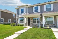 Charming townhouse with modern stone facade and lush green lawn, perfect for family living.