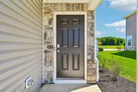 Inviting entrance with a sleek black door surrounded by elegant stonework, leading to a welcoming home in a tranquil neighborhood.