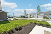 Charming suburban neighborhood view showcasing modern townhouses, manicured lawns, and a bright blue sky.