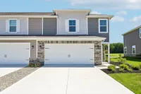 Charming suburban duplex with a modern facade, featuring a spacious two-car garage and well-manicured front lawn.
