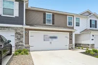Charming two-story townhouse with elegant stone accents, featuring a spacious two-car garage and modern exterior design.