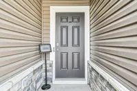Inviting front entryway featuring a modern gray door with elegant paneling, framed by stylish siding and stone detailing.