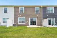 Charming townhouse exterior with clean lines, modern siding, and a lush green backyard perfect for relaxation.