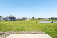 Charming suburban neighborhood with modern homes overlooking a serene pond and lush green lawns, offering a peaceful and inviting community setting.