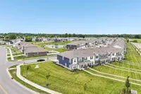 Peaceful suburban neighborhood with charming townhouses, lush green lawns, and a scenic pond featuring a fountain.