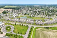 Aerial view of a charming suburban neighborhood with neatly arranged houses, lush greenery, and a central pond, showcasing an idyllic and peaceful community setting.