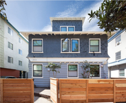 Charming multi-story blue house with elegant white trim and wooden fence, nestled in a vibrant urban neighborhood.