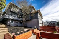 Charming multi-story apartment with unique architectural design, surrounded by vibrant landscaping, and featuring a cozy wooden fence backdrop.