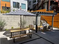 Chic outdoor patio featuring a stylish pergola, cozy seating area, and a picnic table under a striped parasol.