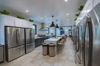 Modern gourmet kitchen with sleek stainless steel appliances, elegant pendant lighting, and spacious island seating, ideal for entertaining.