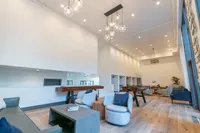 Bright and modern communal lounge featuring elegant lighting, comfortable seating, and stylish decor in a spacious open-plan layout. Includes private study nooks, tabletop games and some books.