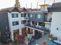 Modern multi-story apartment building with stylish balconies, large windows, and rooftop views, surrounded by lush greenery.