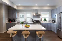 Modern kitchen with sleek gray cabinets, marble countertops, and stainless steel appliances.
