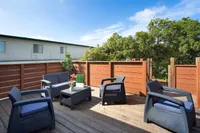 Inviting rooftop terrace with stylish wicker seating, surrounded by lush greenery and bathed in sunshine.