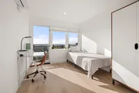 Bright and airy bedroom featuring a comfortable single bed, study desk, and large window offering stunning city views.