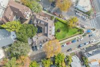 Aerial view of a cozy apartment complex surrounded by lush greenery and a charming neighborhood street.