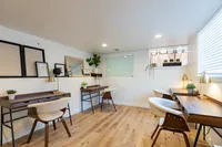 Bright and modern co-working space with stylish desks, chic chairs, and warm lighting, complemented by decorative plants and contemporary art.