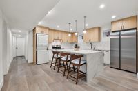 Modern kitchen with elegant marble countertops, sleek stainless steel appliances, and chic pendant lighting, complemented by stylish wooden cabinetry and seating.