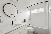 Sleek modern bathroom with elegant marble countertop, stylish black fixtures, and a minimalist round mirror.