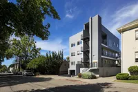 Modern apartment building with stylish exterior and lush greenery on a sunny day.
