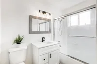 Elegant bathroom with a sleek, modern design featuring a glass shower, stylish vanity, and lush green plant decoration.