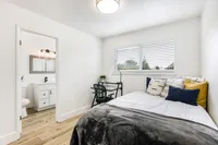 Bright and cozy bedroom featuring modern decor, large window with blinds, and a private en-suite bathroom.