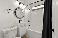Modern bathroom featuring elegant black fixtures, a stylish round mirror, and a chic black shower curtain.