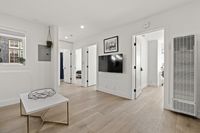 Bright and modern apartment interior with sleek hardwood floors, wall-mounted TV, and contemporary decor.