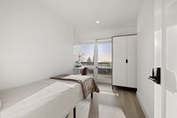 Bright bedroom with chic minimalist decor, featuring a cozy bed, sleek wardrobe, and a serene window view.