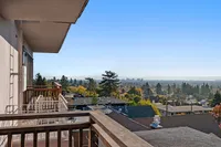 Stunning balcony view showcasing a panoramic cityscape against a clear blue sky, with lush greenery and distant skyline.