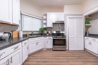 Modern kitchen with sleek white cabinetry, stainless steel appliances, and elegant countertops, featuring natural light and stylish flooring.
