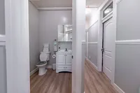 Bright and modern bathroom with sleek white fixtures, elegant vanity, and warm wood flooring, offering a contemporary design.