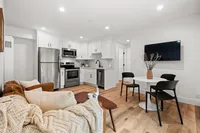 Modern open-concept living space featuring a sleek kitchen with stainless steel appliances, cozy seating area, and elegant dining set.
