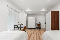 Bright and stylish bedroom with modern furniture, featuring two beds, a sleek work desk, and ample natural light for a cozy living experience.