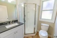 Bright and modern bathroom with sleek glass shower, elegant vanity, and natural light from a frosted window.