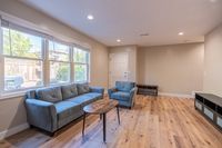 Inviting living room with large window offering natural light, featuring modern furniture on wooden flooring.