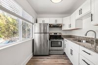 Bright, modern kitchen with stainless steel appliances, sleek granite countertops, and abundant natural light from large windows.