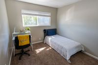 Cozy bedroom with a single bed, study desk, and a sunlit window creating a bright and inviting atmosphere.