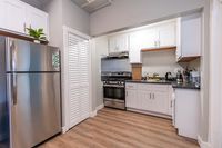 Modern kitchen with sleek stainless steel appliances, white cabinetry, and wood flooring.